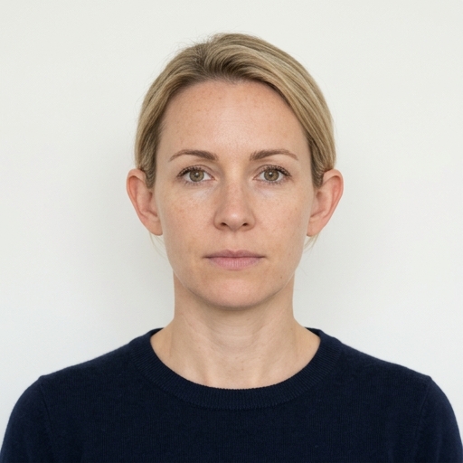Even-light passport-style headshot of an adult facing camera on a plain off-white background